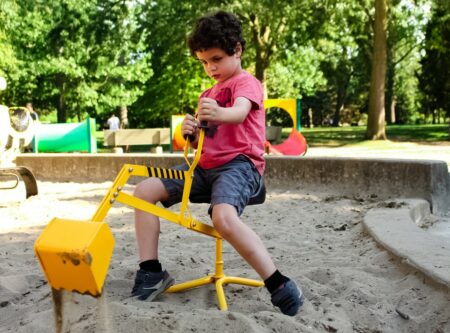 Jeune garçon jouant avec une pelle mécanique dans un bac à sable