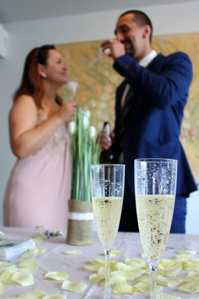 Mariés buvant du champagne en fond avec deux coupes flûtes de champagne en premier plan