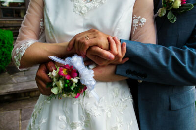 Plan serré sur les mains de jeunes mariés tenant le bouquet de mariage