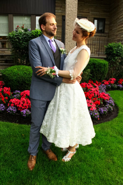Jeunes mariés s'enlaçant devant un parterre de fleurs