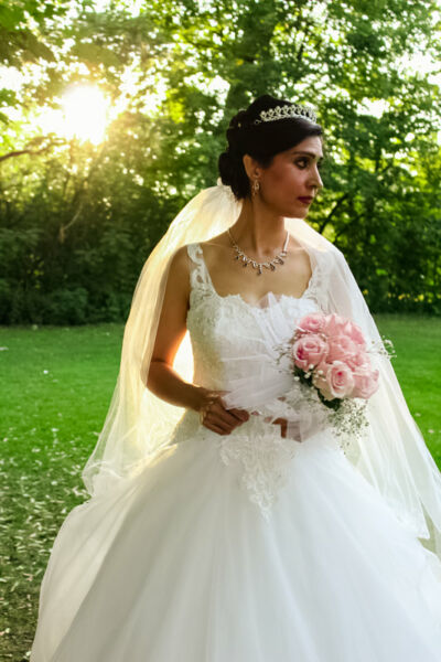 Plan moyen avec femme en robe de mariage bouquet à la main sur fond verdoyant