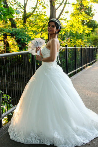 Jeune femme en robe de mariage tenant le bouquet sur un pont 2