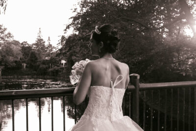 Jeune femme en robe de mariage tenant le bouquet sur un pont