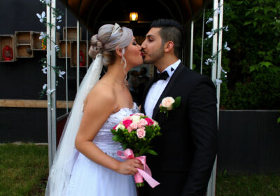 Jeunes mariés s'embrassant avec la femme tenant un bouquet