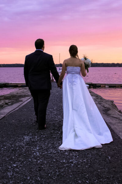 Mariés se tenant la main et regardant au loin devant une étendue d'eau