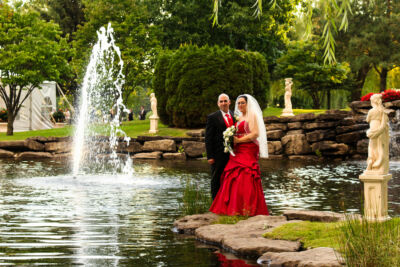 Mariés posant au loin devant un bassin d'eau avec fontaine