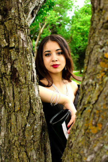 Jeune femme élégante posant entre deux troncs d'arbres